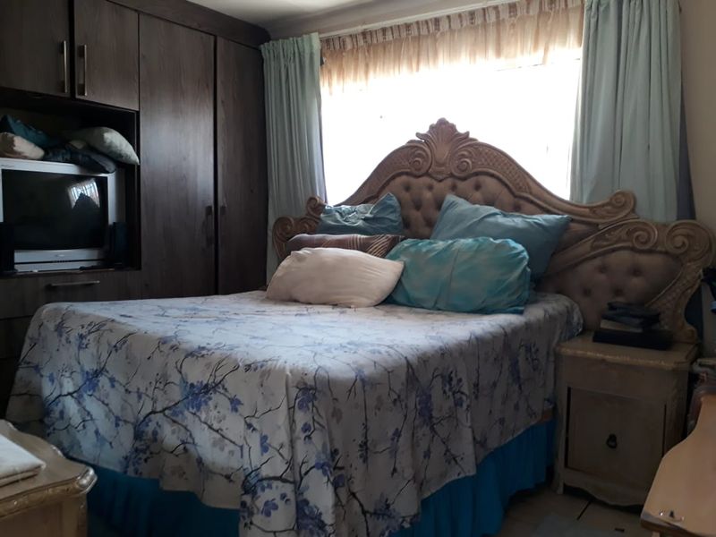 A bedroom featuring built-in dark wood cabinetry and a large window with curtains.