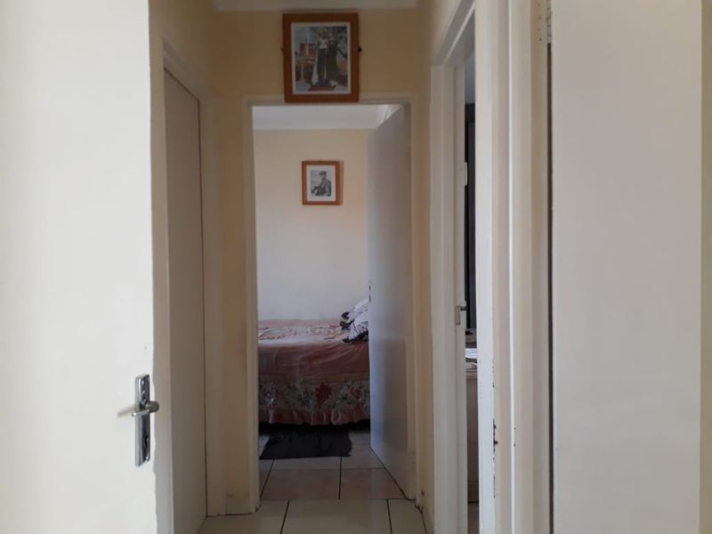 A functional residential hallway with tiled flooring providing access to adjacent bedrooms and living areas.