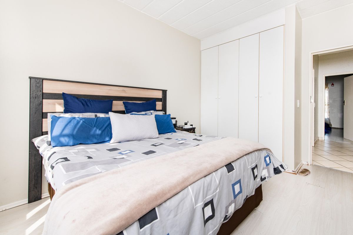 A bedroom featuring built-in cupboards and light-toned laminate flooring, offering a functional and neutral space.