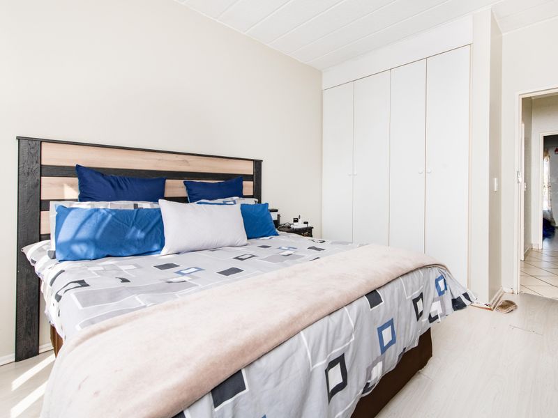 A bedroom featuring built-in cupboards and light-toned laminate flooring, offering a functional and neutral space.
