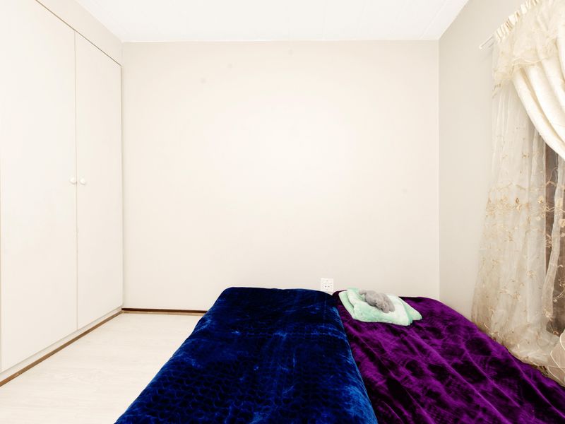 A simple bedroom featuring light-toned laminate flooring and a full-height built-in wardrobe, offering a clean and neutral foundation for personalization.