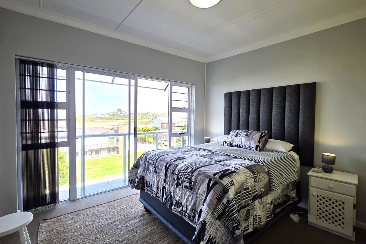 A well-lit bedroom featuring a large sliding glass door that opens onto a balcony, providing natural light and views.