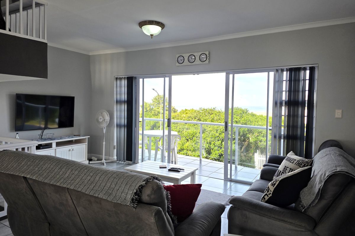 Spacious living room featuring large sliding glass doors that open onto a balcony, providing natural light and scenic outdoor views.