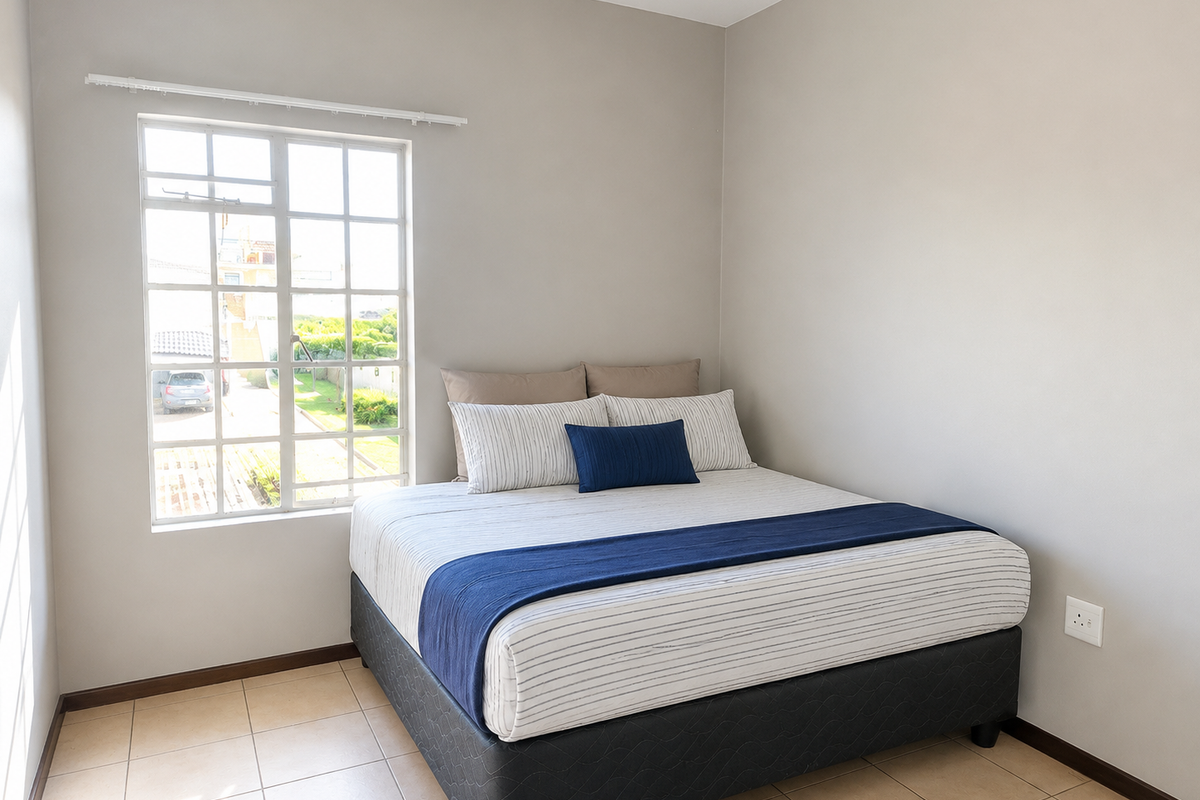 A clean, neutral-toned bedroom featuring tiled flooring and a large grid-pattern window that allows for natural light.