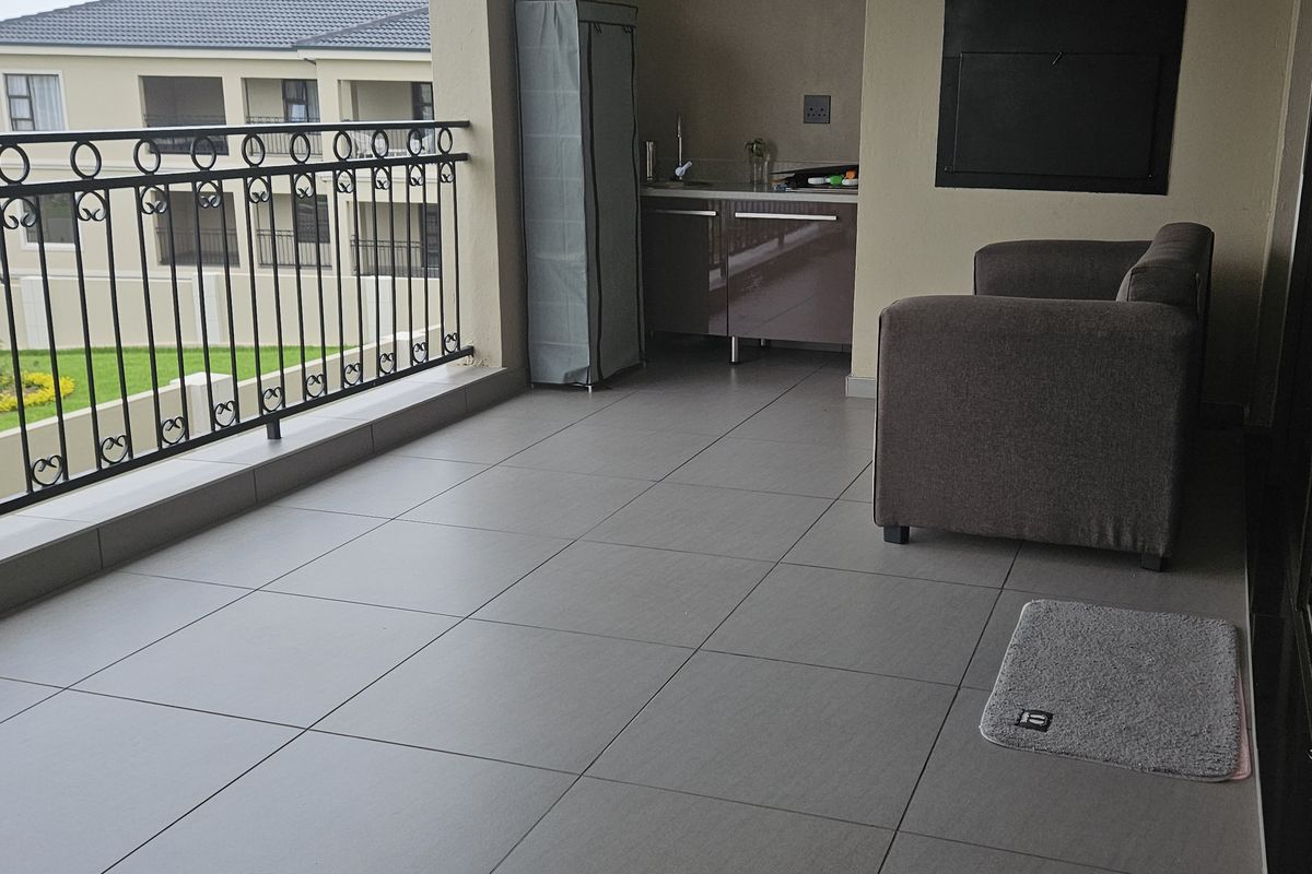 Covered balcony featuring tiled flooring, a wrought iron balustrade, built-in cabinetry with a sink, and a built-in braai area.