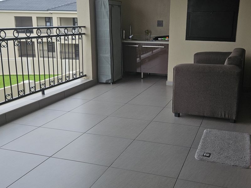 Covered balcony featuring tiled flooring, a wrought iron balustrade, built-in cabinetry with a sink, and a built-in braai area.