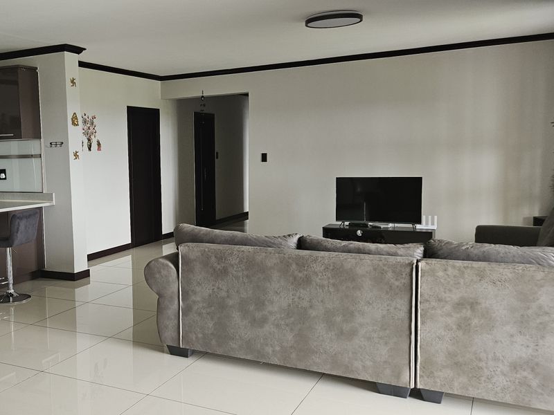 Open plan living area featuring polished tile flooring, neutral walls, and a seamless transition to the kitchen space.