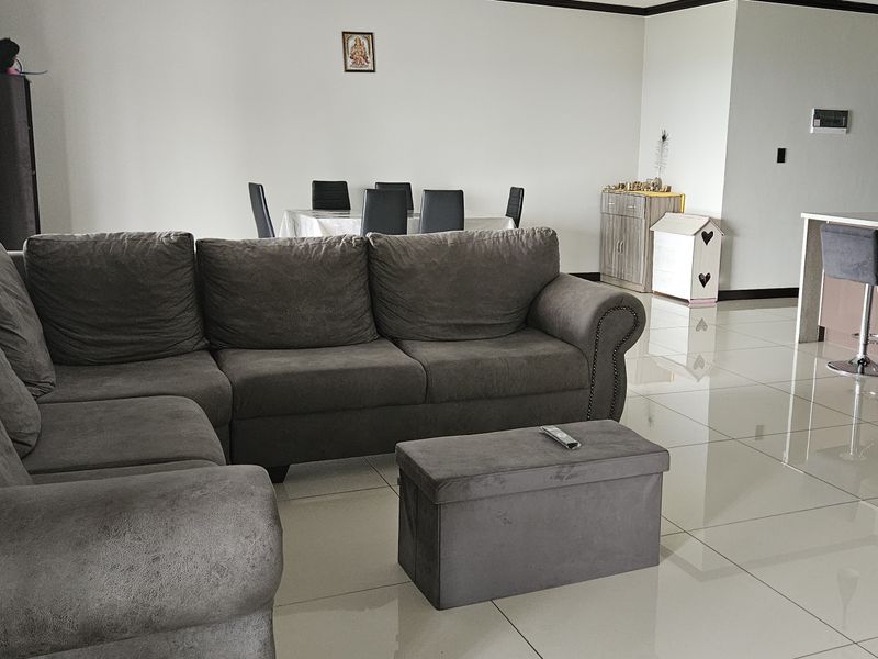 Spacious open-plan living and dining area featuring polished porcelain floor tiles and a modern kitchen island with breakfast bar seating.