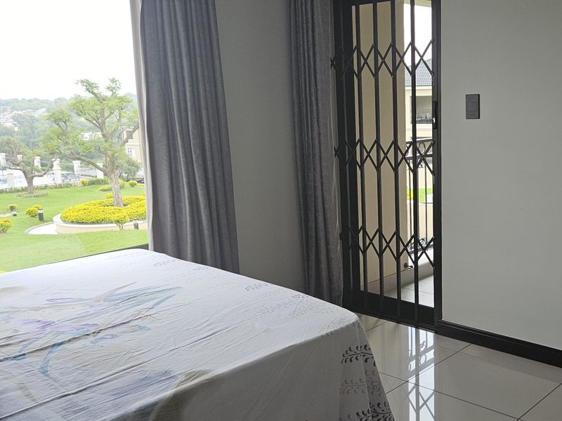 Bright bedroom featuring large windows with garden views and direct access to an outdoor area through a secure sliding door.