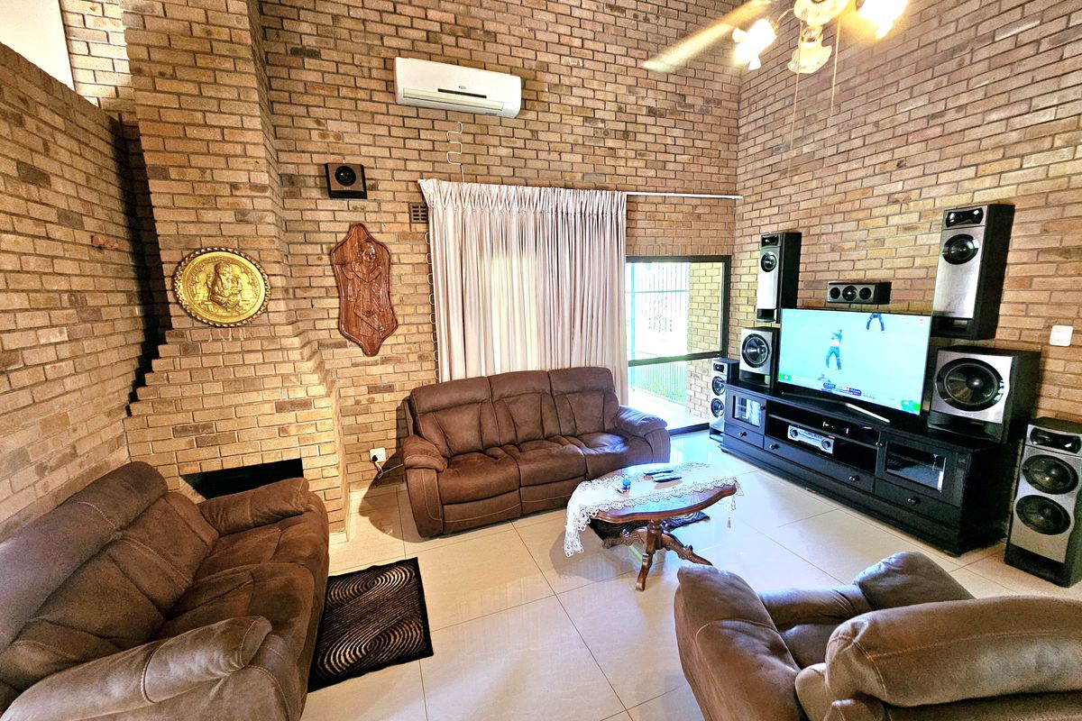 Spacious living room featuring a prominent brick fireplace, tiled flooring, and a split-system air conditioner, offering a warm and textured aesthetic.