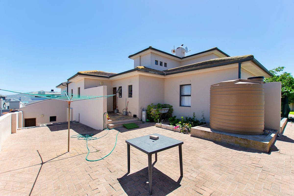 Rear exterior view of the property featuring a paved patio area and a large water storage tank.