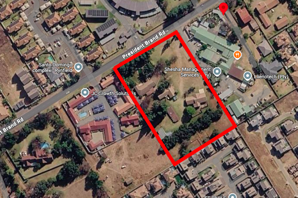 Aerial view of a residential vacant land plot featuring existing structures and mature trees, situated in a developed suburban neighborhood.