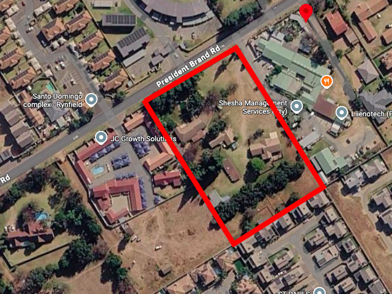 Aerial view of a residential vacant land plot featuring existing structures and mature trees, situated in a developed suburban neighborhood.