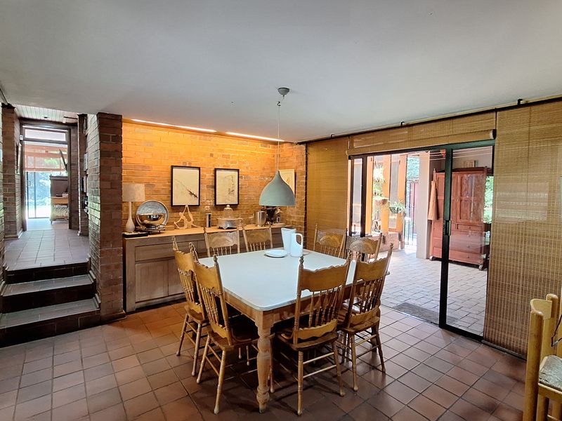 Spacious dining area featuring exposed brick walls, terracotta floor tiles, and large sliding glass doors providing seamless access to the outdoor patio.