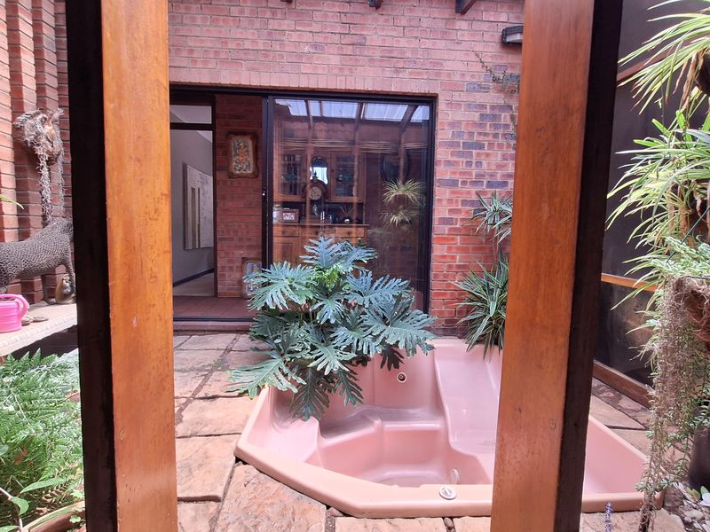 A private courtyard featuring a built-in spa bath, exposed brick walls, and stone paving, providing a secluded outdoor relaxation area.