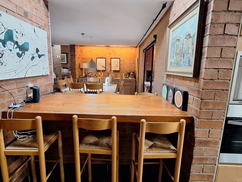 Open plan kitchen and dining area featuring exposed brick walls, a built-in breakfast bar, and integrated wall-mounted oven and microwave.