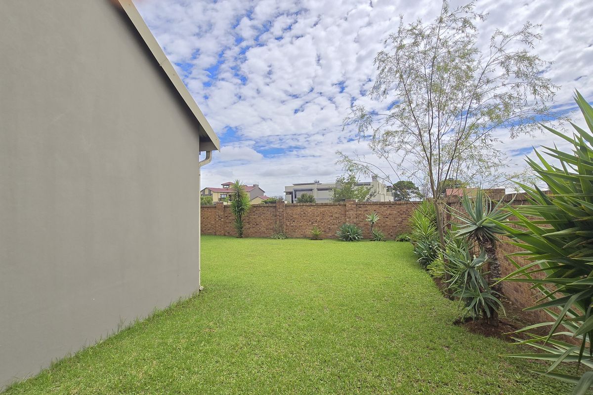 A well-maintained rear garden featuring a lush green lawn and a solid brick boundary wall, providing privacy and outdoor space.