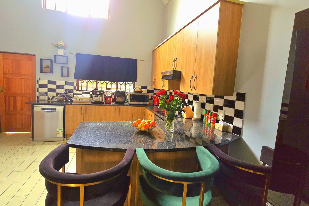 A functional kitchen featuring wooden cabinetry, granite countertops, a checkered tile backsplash, and a breakfast bar area with integrated appliances.