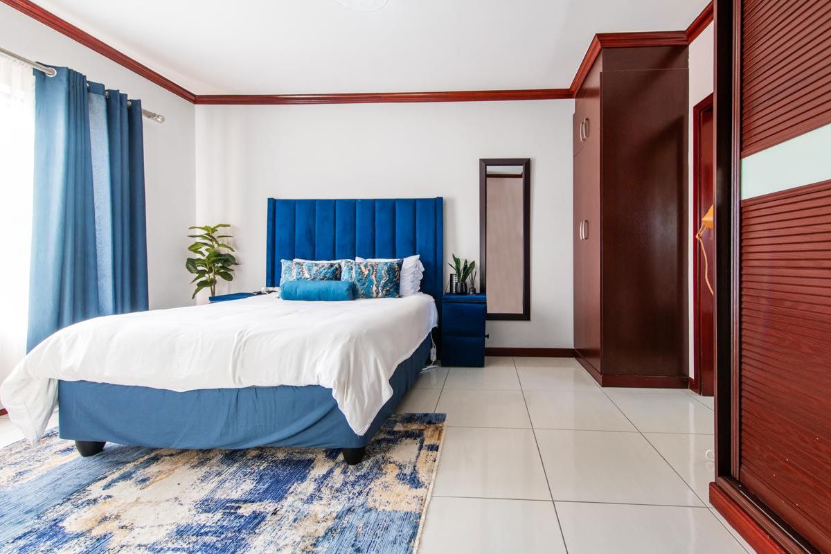 A well-maintained bedroom featuring tiled flooring, built-in dark wood cabinetry, and crown molding detail.