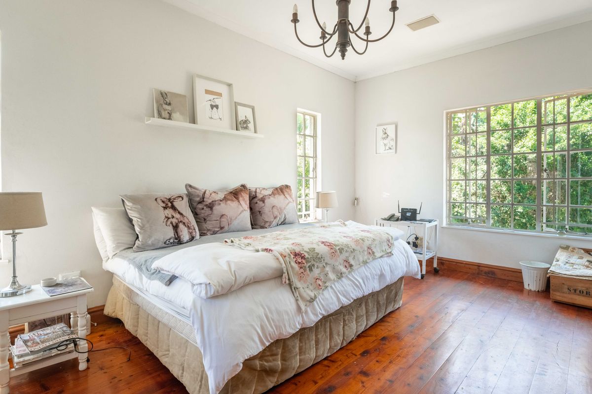 Spacious bedroom featuring original hardwood flooring, classic cove molding, and large windows that provide ample natural light and garden views.