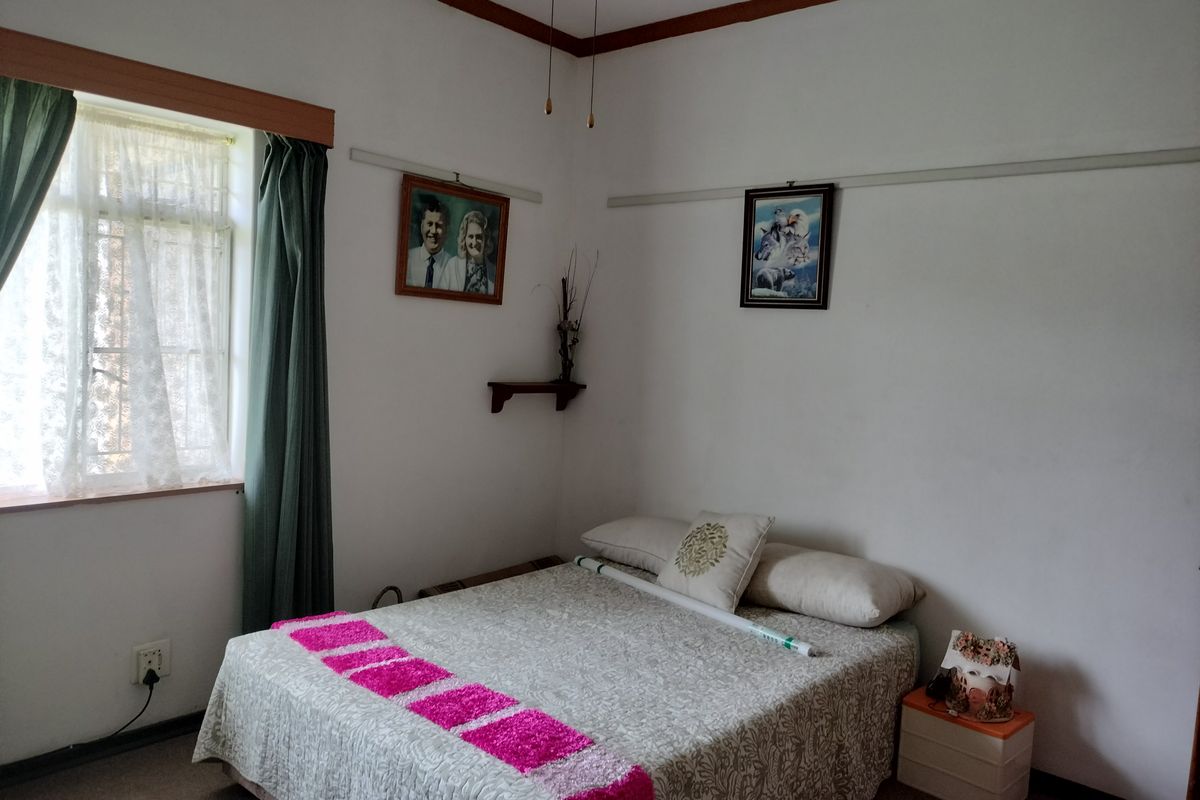 A standard bedroom featuring a window with timber framing and a traditional picture rail, offering a functional and well-maintained living space.