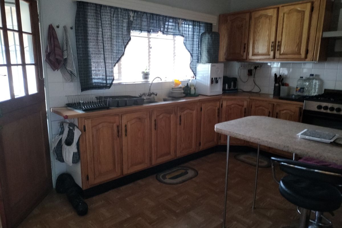 A functional kitchen featuring traditional wooden cabinetry, laminate countertops, and a tiled backsplash, offering potential for a modern cosmetic update.