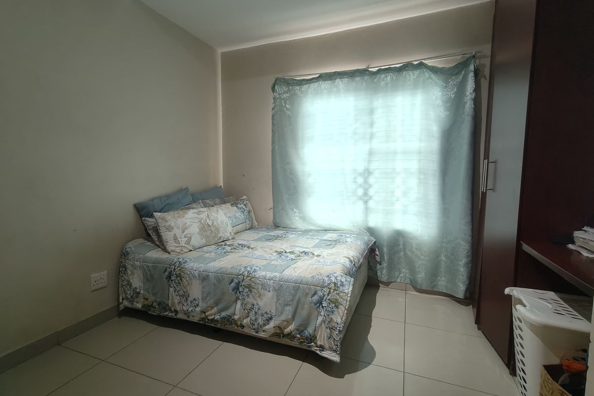 A functional bedroom featuring neutral tiled flooring and a built-in wardrobe, providing practical storage space.
