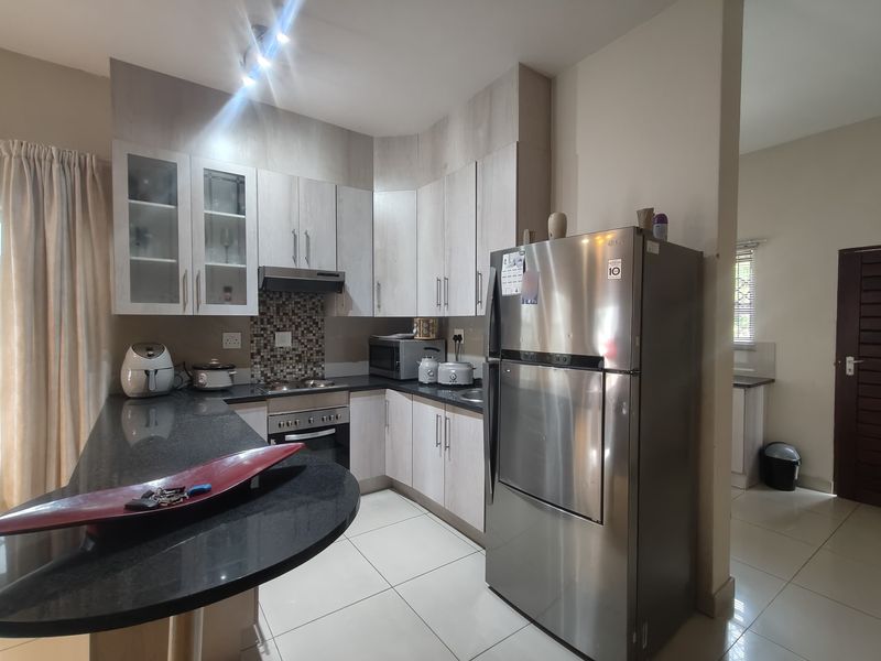 A functional kitchen featuring light wood-finish cabinetry, granite countertops, a built-in oven with extractor fan, and a mosaic tile backsplash.