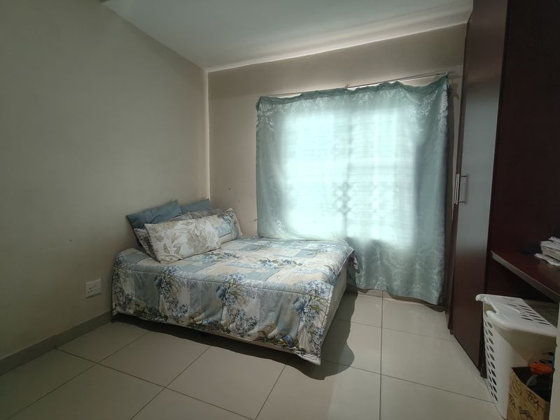 A functional bedroom featuring neutral tiled flooring and a built-in wardrobe, providing practical storage space.