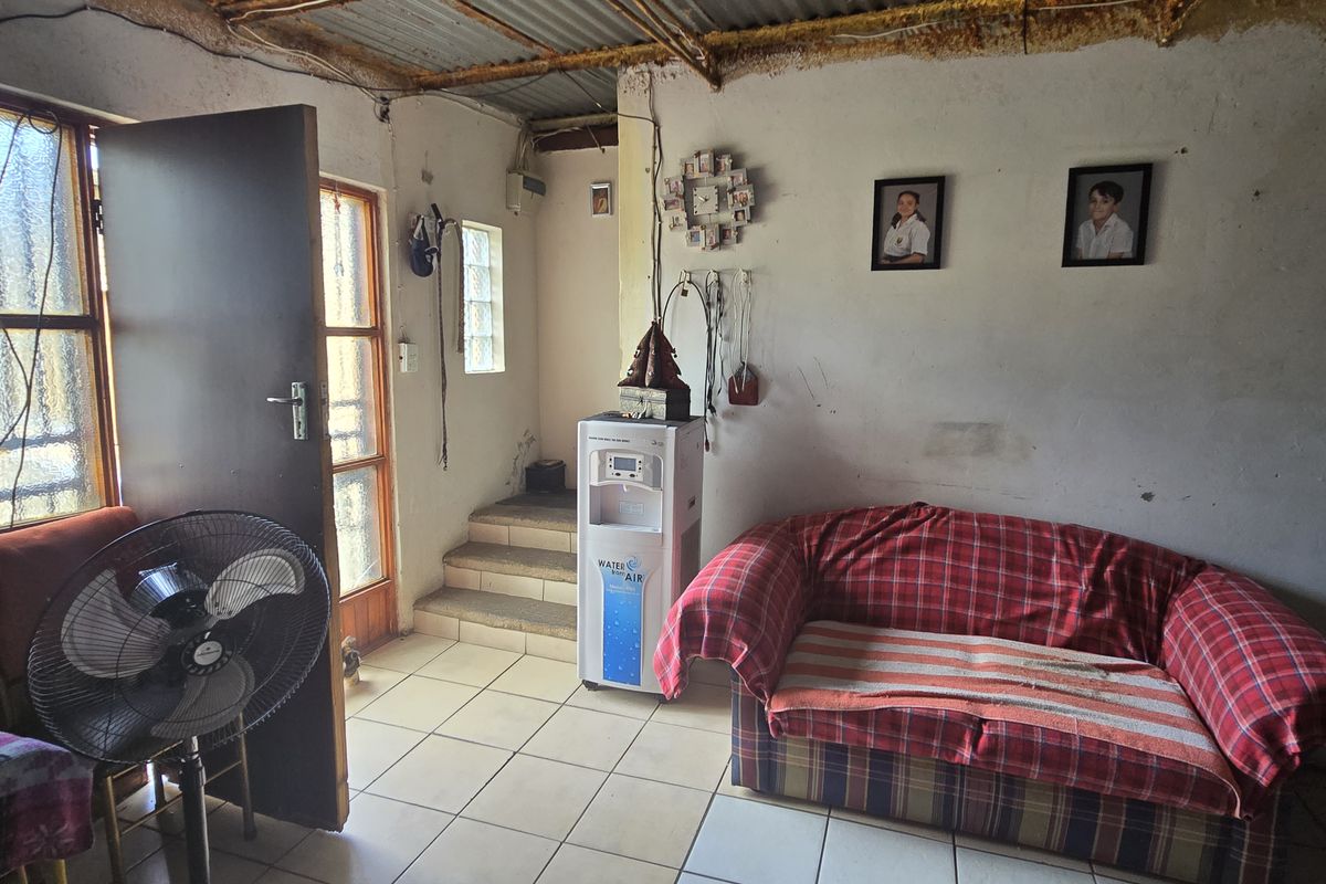 A living area featuring tiled flooring, a corrugated metal ceiling, and a small set of steps leading to an adjacent space.