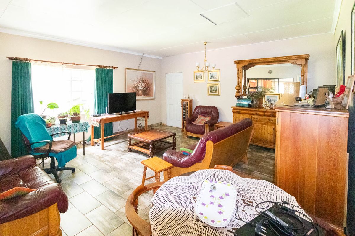 A spacious living room featuring tiled flooring and a built-in mirror unit, offering a functional layout with ample natural light.