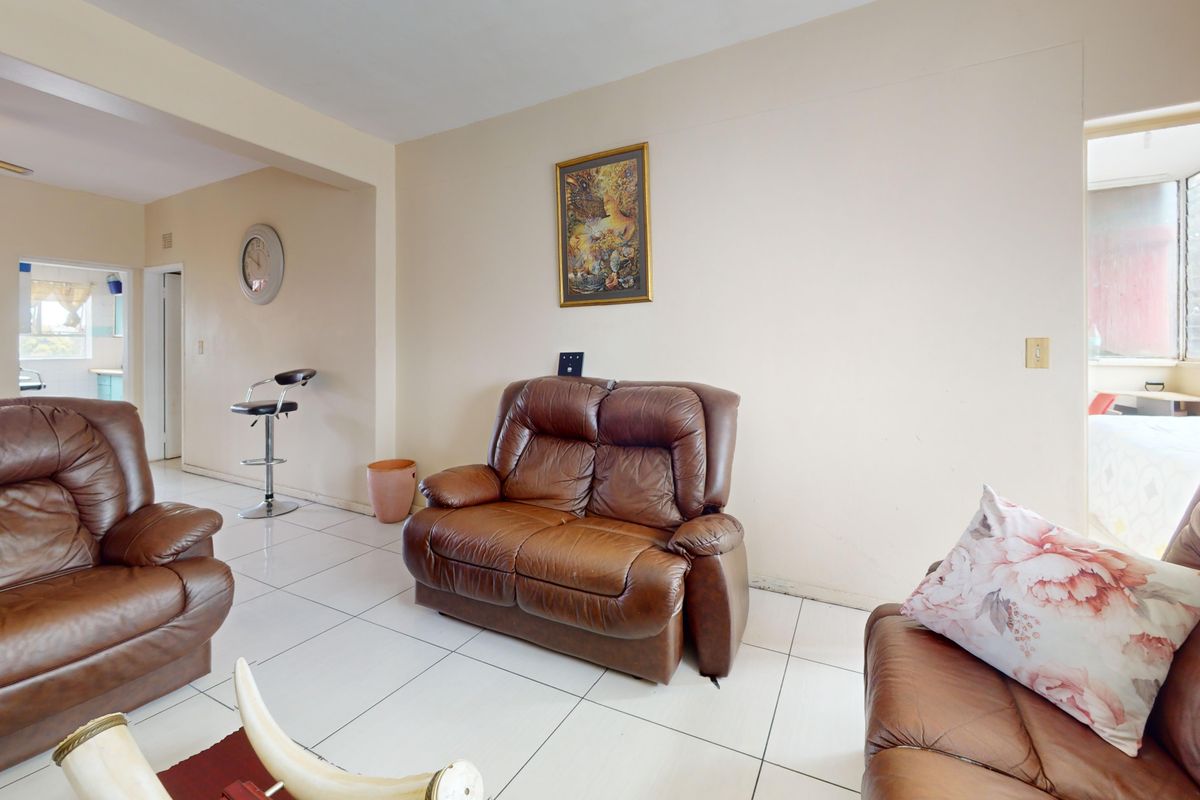 A living room featuring tiled flooring and a ceiling fan, with an open-plan layout connecting to adjacent spaces.