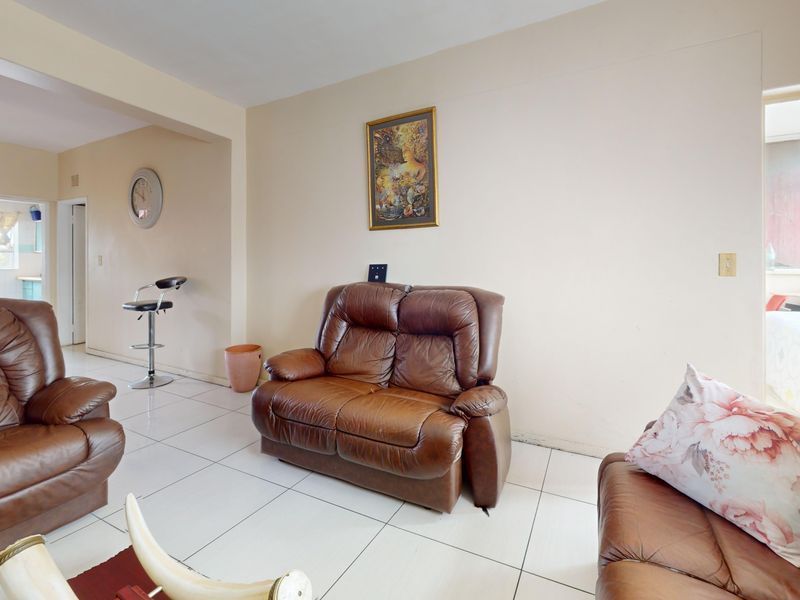 A living room featuring tiled flooring and a ceiling fan, with an open-plan layout connecting to adjacent spaces.
