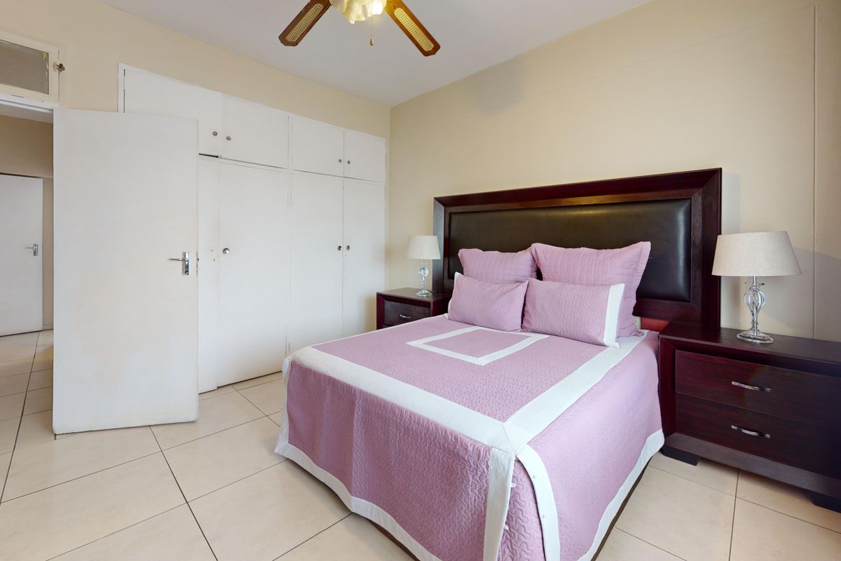 A bedroom featuring tiled flooring, a ceiling fan, and ample built-in cupboard storage space.