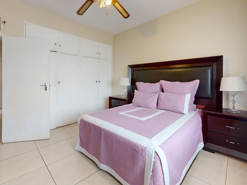 A bedroom featuring tiled flooring, a ceiling fan, and ample built-in cupboard storage space.