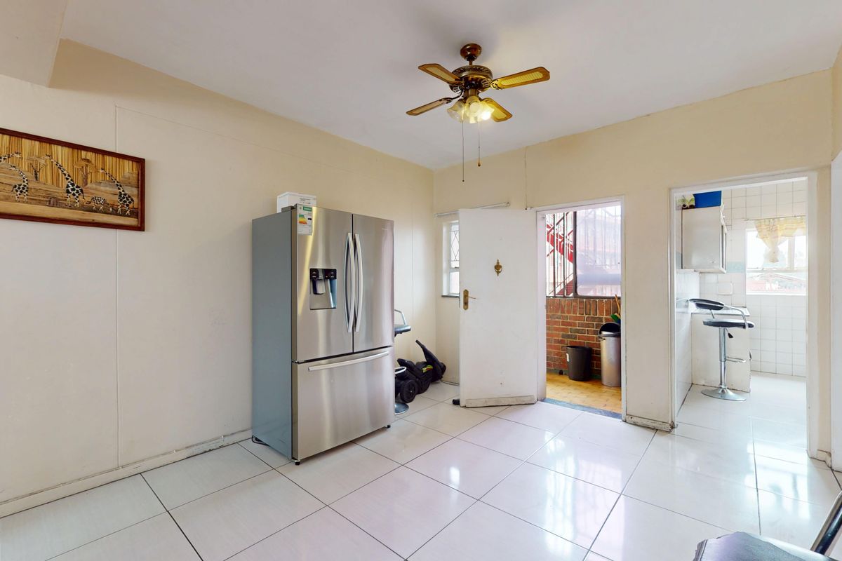 A functional kitchen area featuring tiled flooring and a ceiling fan, with direct access to an exterior entrance and an adjacent utility space.