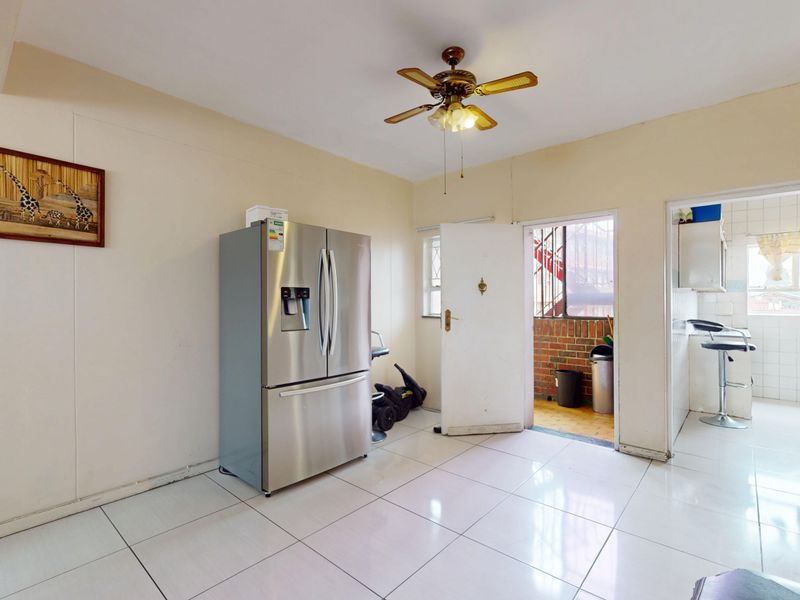 A functional kitchen area featuring tiled flooring and a ceiling fan, with direct access to an exterior entrance and an adjacent utility space.