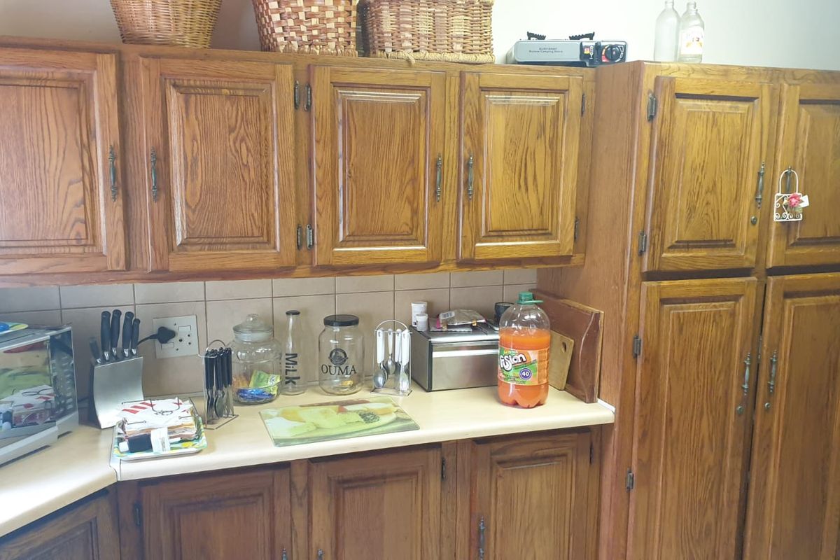 A functional kitchen featuring traditional oak cabinetry, laminate countertops, and a tiled backsplash, offering a classic aesthetic with ample storage space.