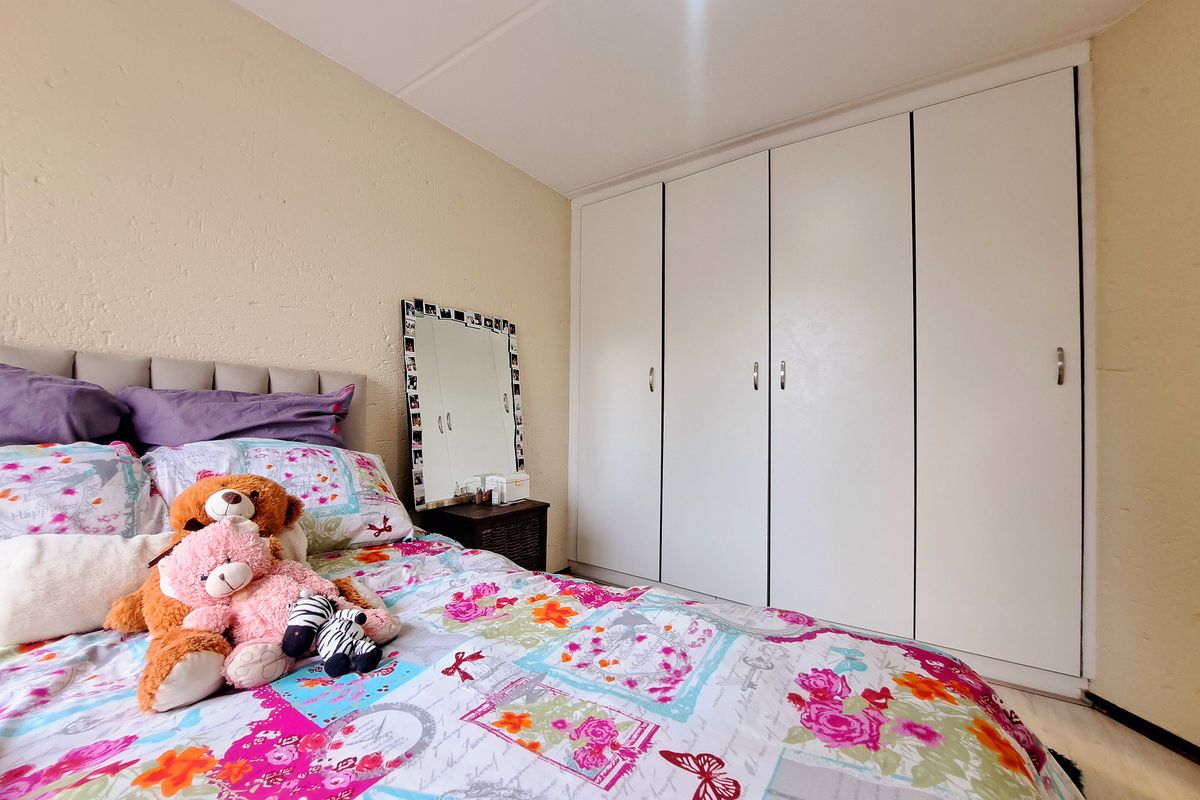 A bedroom featuring a large, white built-in wardrobe with four doors, providing ample storage space.