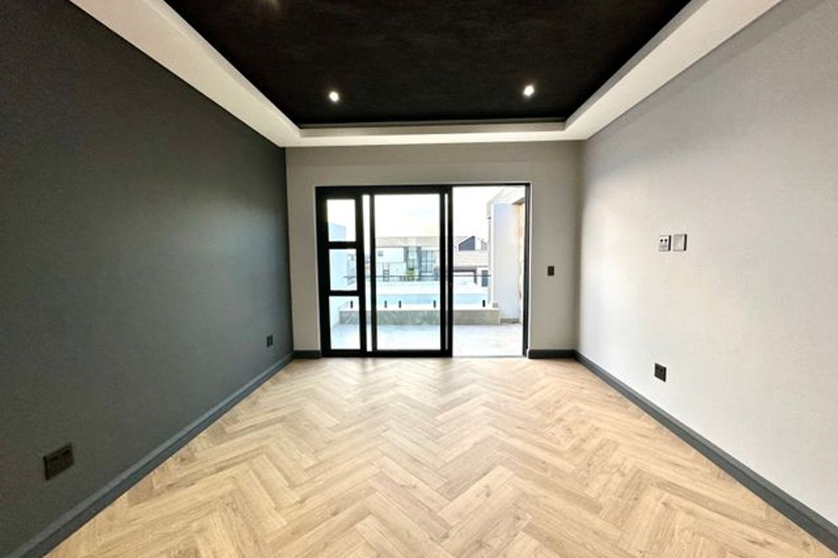 Modern living room featuring herringbone wood-look flooring, a recessed tray ceiling with integrated downlights, and large sliding glass doors leading to an outdoor patio.