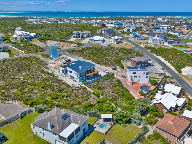 An aerial view of a residential coastal neighborhood showing the surrounding landscape, street layout, and proximity to the ocean.