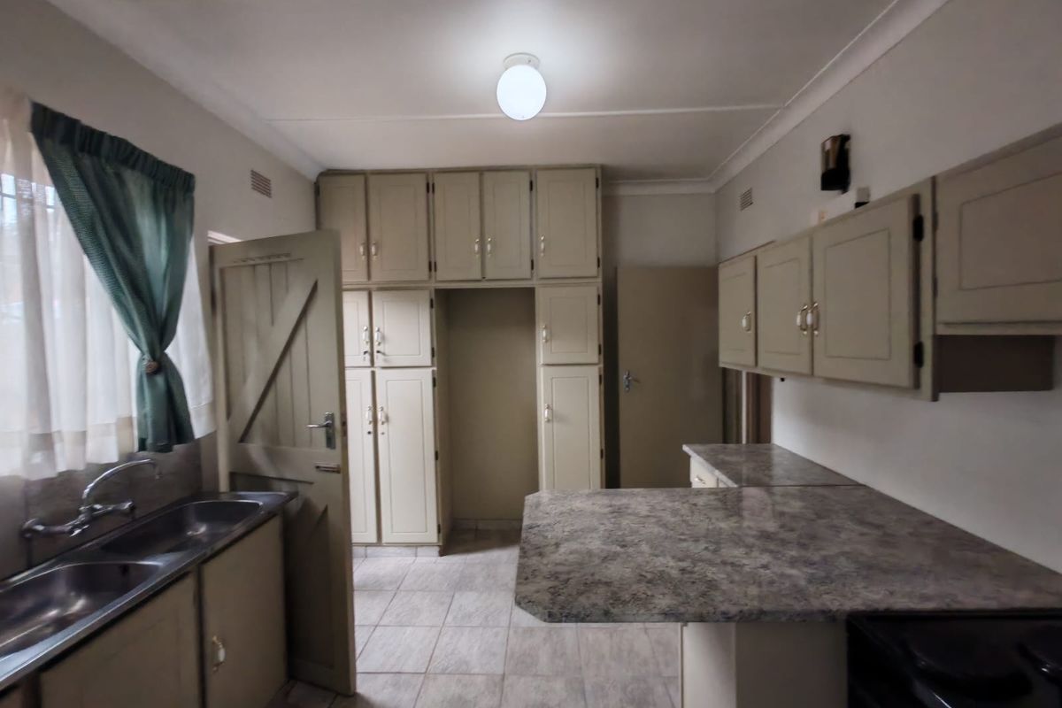 A functional kitchen featuring ample built-in cabinetry, laminate countertops, and a double bowl stainless steel sink with tiled flooring.