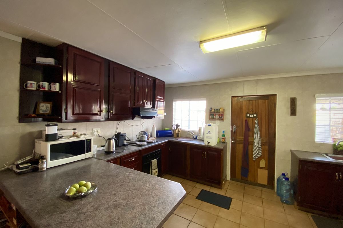 A functional kitchen featuring dark wood cabinetry, laminate countertops, and tiled flooring, offering a traditional layout with ample storage and workspace.