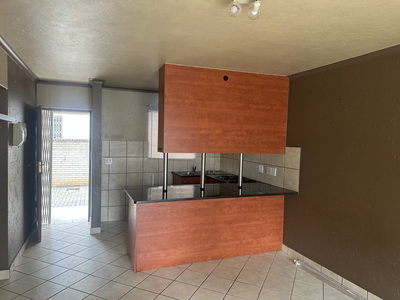 Open plan kitchen area featuring a breakfast bar, tiled flooring, and direct access to an exterior space through a security gate.