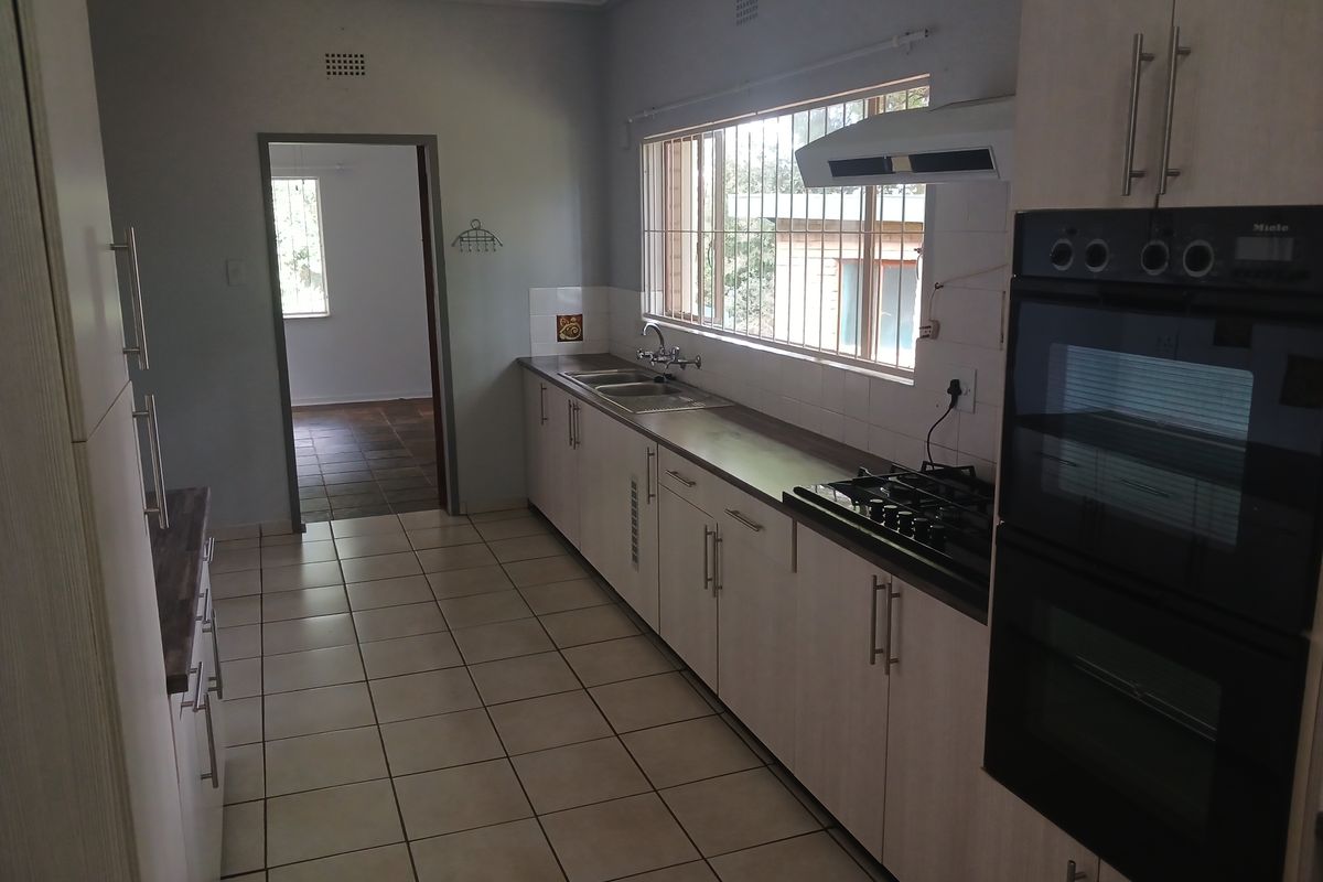 A functional kitchen featuring light-toned cabinetry, built-in double oven, gas hob, and tiled flooring, offering a clean and practical workspace.