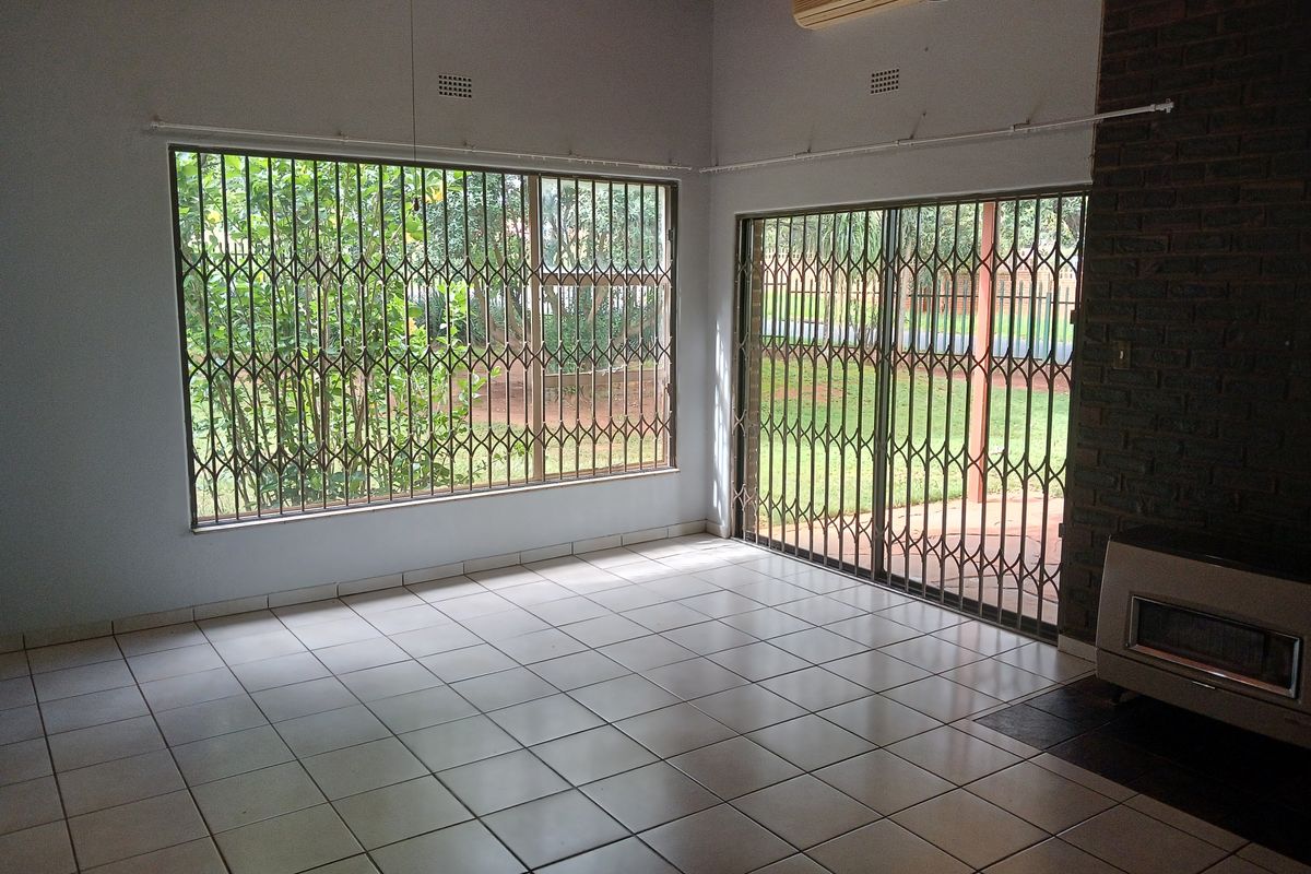 Spacious living area featuring tiled floors, an exposed brick fireplace with a built-in insert, and large sliding doors leading to the garden.