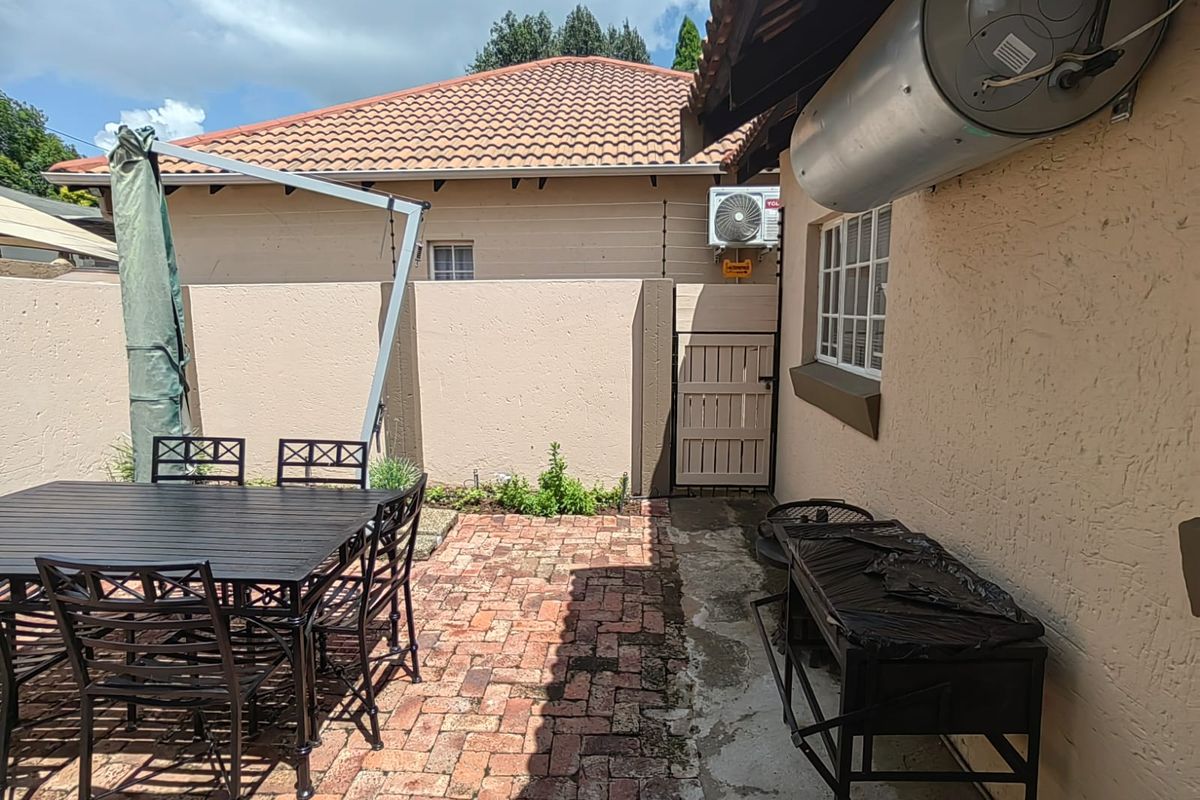 Rear courtyard area featuring brick paving, boundary wall with electric fencing, and external geyser installation.