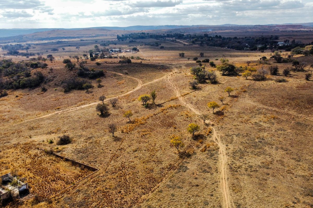 Aerial view of expansive vacant residential land featuring natural vegetation, dirt access tracks, and the remains of a small derelict structure.