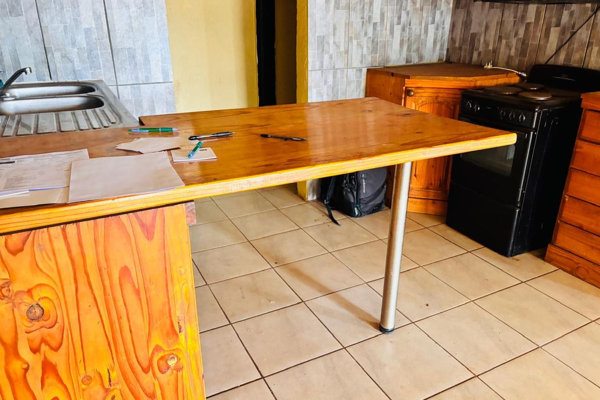 A functional kitchen area featuring a wooden breakfast bar, tiled splashbacks, and built-in cabinetry with a freestanding stove.