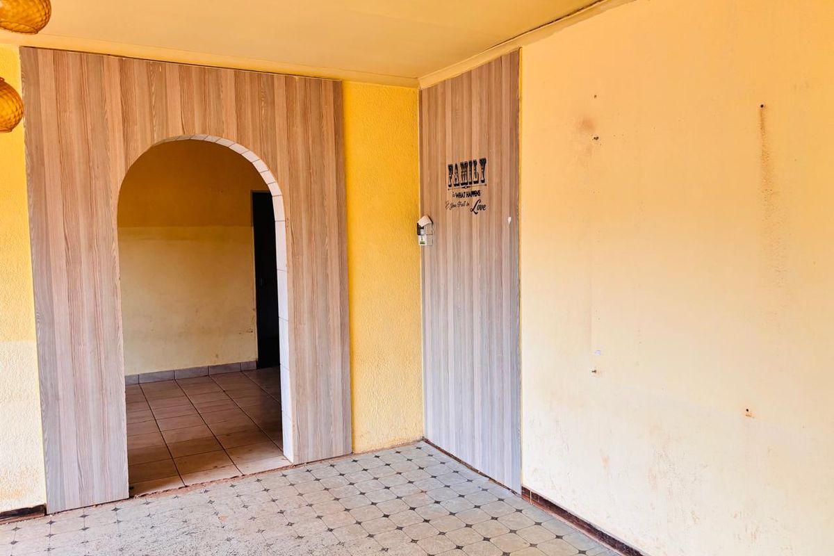 An interior living space featuring a decorative arched doorway with wood-look paneling and tiled flooring.